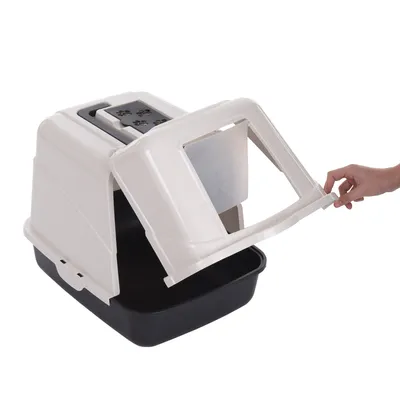 Hand öffnet die Klappe einer geschlossenen Katzentoilette mit schwarzer Unterschale und beiger Haube, Sicht auf den Innenraum.