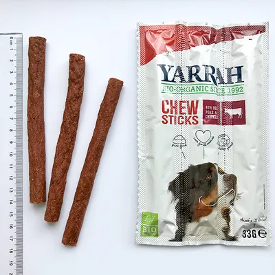 Yarrah Chew Sticks -pussi, jossa tekstiä: '93% beef, pork & chicken', 'BIO', 33 g. Kolme purutikkuja viivottimen vieressä näyttää pituuden noin 15 cm.