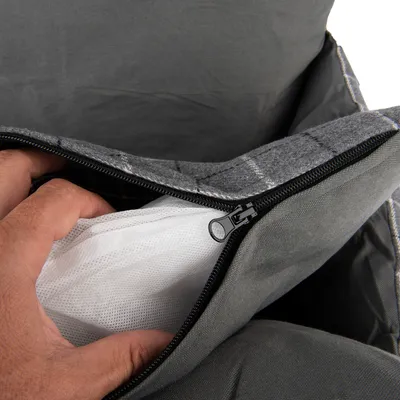 Close-up of a hand pulling white mesh material from a grey zip compartment.