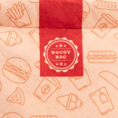 Etichetă Doggy Bag pe material bej cu ilustrații roșii de articole tip fast-food precum burger, cartofi prăjiți și pizza.