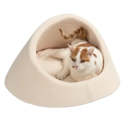 Katzenhöhle aus beigem Stoff mit einer weissen und braun getupften Katze, die darin liegt.