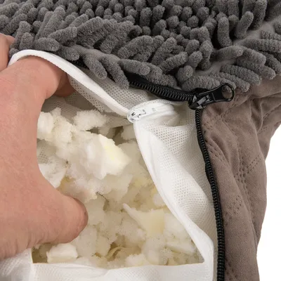 Nahaufnahme eines geöffneten Reissverschlusses mit sichtbarer Füllung aus weissem Schaumstoff in einem grauen Stoffbezug.
