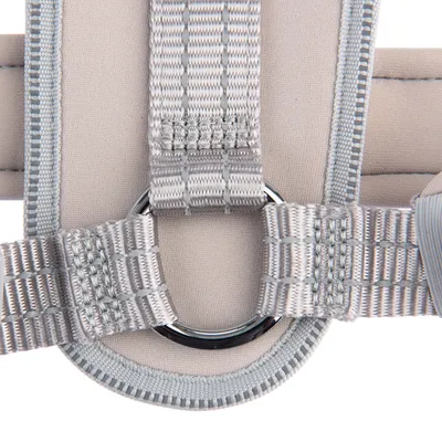 Close-up van een grijs tuigje met stevige naden en een metalen ring voor bevestiging.