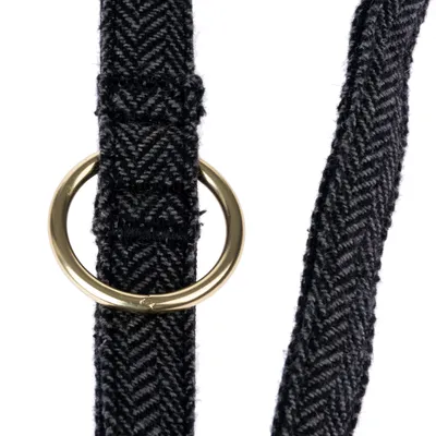 Close-up of a black fabric strap with herringbone pattern and a gold-coloured metal ring.