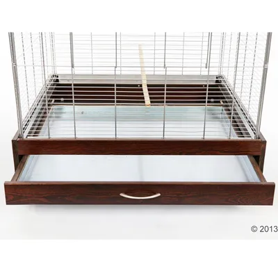 Клетка с метални решетки и дървена основа, изтегляща се метална тава за почистване и дръжка отпред. Видим е един дървен прът вътре в клетката.