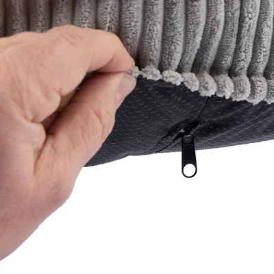 Detailní záběr na šedý, strukturovaný potah s zipem a protiskluzovou spodní stranou. Ruka ukazuje snímatelnou funkci potahu.