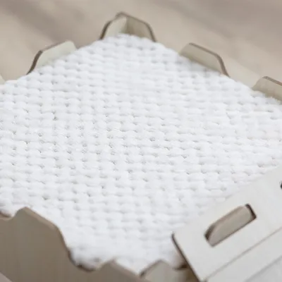 Superficie blanca y texturizada en una caja de madera. Foto de detalle del material, posiblemente para productos o accesorios para mascotas.