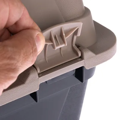 Close-up van een beige-grijs sluitsysteem dat door een hand wordt geopend. Toont de functie van het deksel voor veilig afsluiten van een container.