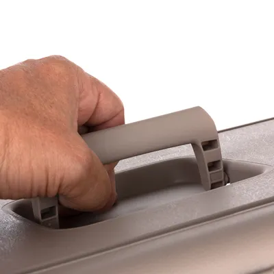 Close-up van een hand die een grijze draaggreep optilt. Toont de functionaliteit van het handvat voor transport.