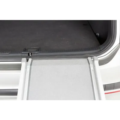 Aluminiowa rampa prowadząca do bagażnika samochodu, widoczna powierzchnia antypoślizgowa i krawędzie zabezpieczające po bokach.