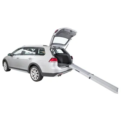 Srebrny samochód kombi z otwartym bagażnikiem i rozłożoną metalową rampą prowadzącą do wnętrza bagażnika.