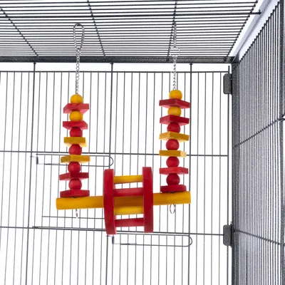 Bird cage with hanging toy made of wood and metal chains, red and yellow elements in geometric shapes.