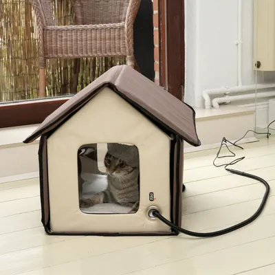 Heated cat house with brown roof and window, suitable for indoor use. Power cable visibly connected.