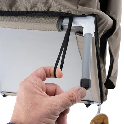 Hand toont hoe een elastische band aan een metalen frame wordt bevestigd. Detailopname van een product met stoffen bekleding en frame.