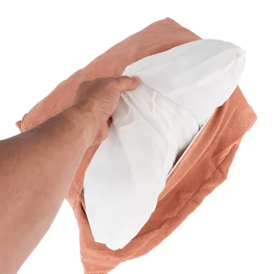 Roka odpira prevleko za blazino v terakota barvi, prikazuje odstranljivo notranjo blazino z belo prevleko.