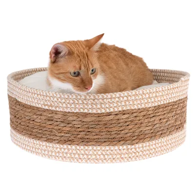 Panier rond en corde tressée beige et marron avec coussin blanc, chat roux et blanc allongé à l’intérieur. Matériaux visibles : corde, tissu.
