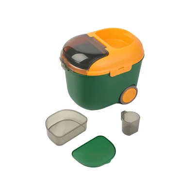 Contenedor de comida verde y amarillo con ruedas, tapa transparente, vaso medidor y recipiente adicional. Accesorios visibles: tapa, recipiente y vaso medidor.