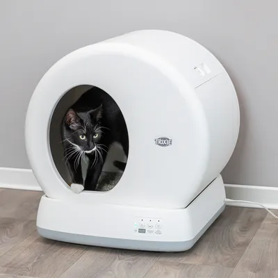 Trixie автоматична котешка тоалетна в бяло с черна котка, видими контролни елементи и LED дисплеи.