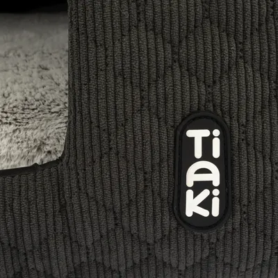 Logo Tiaki visibile su tessuto strutturato grigio scuro con morbida imbottitura interna grigia.