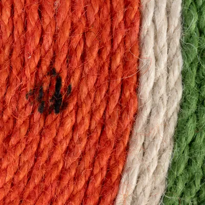 Primer plano de cuerda trenzada en colores naranja, blanco y verde. Estructura del material visible.