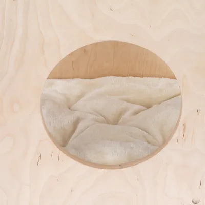 Rundes Holzdesign mit weicher, cremefarbener Polsterung im Inneren. Sichtbare Öffnung zeigt die gepolsterte Fläche.