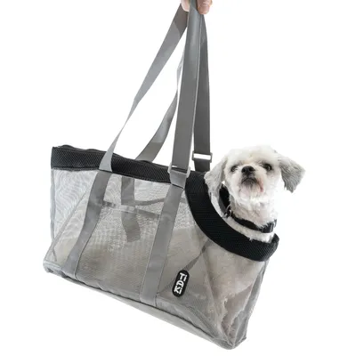 Sac de transport en maille grise Trixie avec anses, contenant un petit chien blanc à poils courts. Marque Trixie visible sur l’étiquette du sac.
