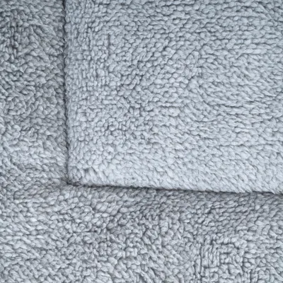 Prim-plan al unui material textil gri, moale, cu textură pufoasă.