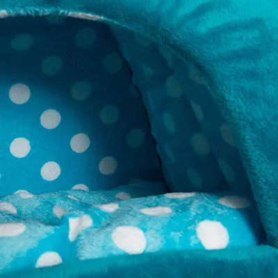 Sisänäkymä pehmustetusta, turkoosista lemmikkipedistä, jossa on valkoisia pisteitä pehmeällä kankaalla.