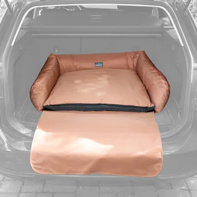 Коричневая собачья лежанка с откидным защитным ковриком, размещена в багажнике автомобиля. Видна фирменная этикетка на задней стороне лежанки.