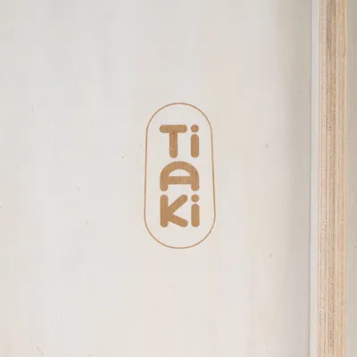 Tiaki. Márkanév világos fa háttéren.