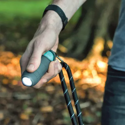 Hand houdt een hondenriem met geïntegreerd LED-licht, geschikt voor wandelingen in het donker.