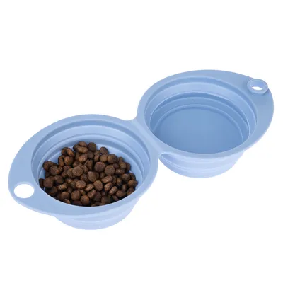 Foldable double feeding bowl made of blue silicone, one bowl filled with dry food, the other empty.