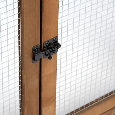 Détail d’une porte en bois avec grillage métallique et loquet noir, montrant le système de fermeture visible sur l’image.