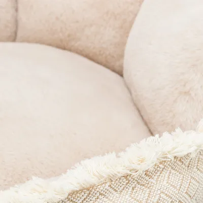 Nahaufnahme eines beigen, flauschigen Stoffes mit Fransen und gewebtem Muster am Rand.