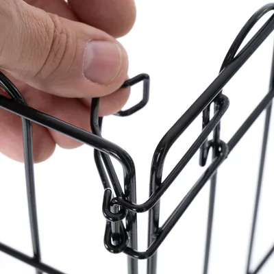 Fermeture en métal noir d'une cage ou barrière, gros plan sur le système de verrouillage avec une main tenant la structure.