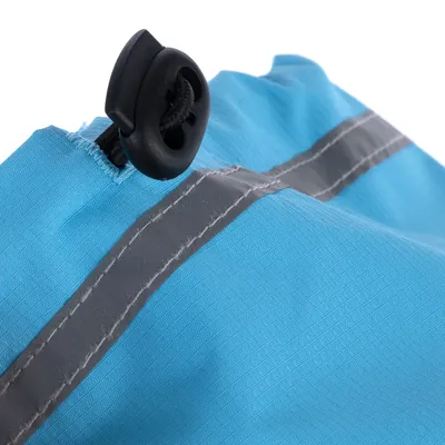 Détail d’un sac bleu en tissu avec cordon de serrage noir et bande grise réfléchissante visible sur la couture.