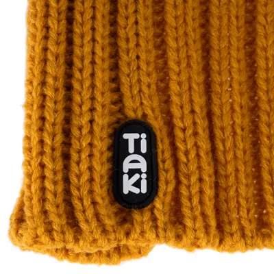Tiaki-Logo auf gestricktem, senfgelbem Stoff.