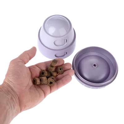 Lila foderleksak, öppen, med hand full av godbitar. Visar påfyllning och användning av leksaken.