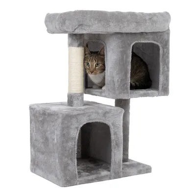 Árbol rascador gris con dos cuevas, una superficie para tumbarse arriba y un poste rascador de sisal. Gato sentado en la cueva superior.
