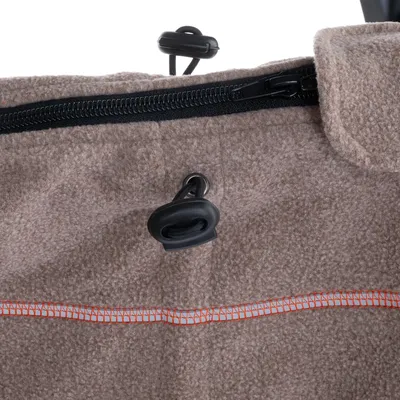 Gros plan sur une fermeture éclair noire et un cordon de serrage avec stoppeur en plastique sur tissu beige à couture orange, matière polaire visible.