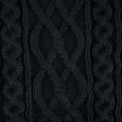 Gros plan sur un tricot noir à motif torsadé, matière laine visible.