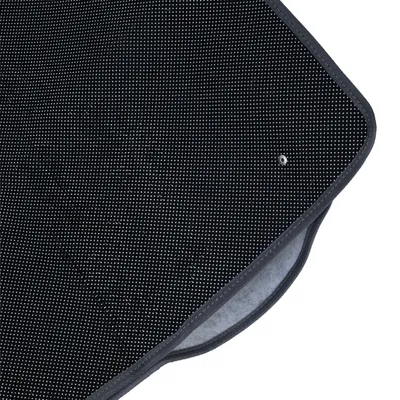 Vue rapprochée d’un tapis noir à surface antidérapante avec petits points blancs et bordure grise, matériau textile visible sur le dessous.