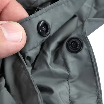 Detailaufnahme von grauem Stoff mit Druckknöpfen, zeigt die Befestigungsmöglichkeit des Materials.