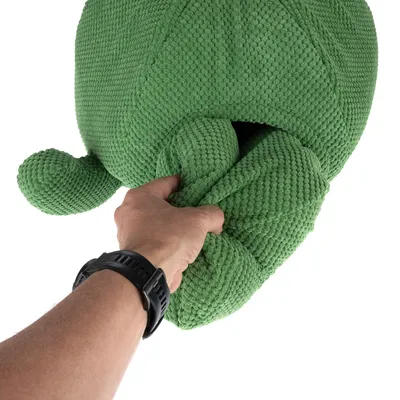 Una mano afferra un gioco di stoffa verde strutturato con apertura. Mostra la flessibilità e la maneggevolezza del materiale.