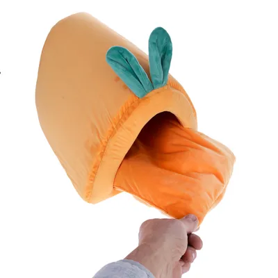 Niche en tissu orange avec coussin amovible, forme de carotte et deux feuilles vertes sur le dessus, tenue par une main.