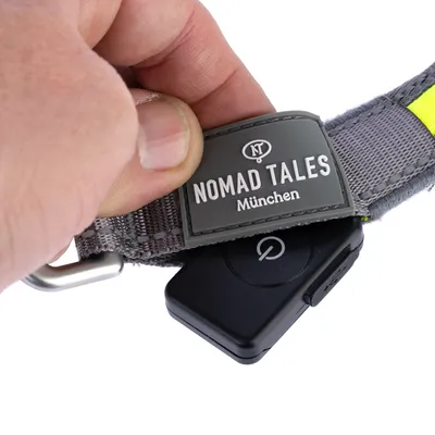 Nomad Tales München Hundehalsband mit grauem Stoff, gelbem Akzent und schwarzem Gerät mit Ein-/Ausschalt-Symbol.