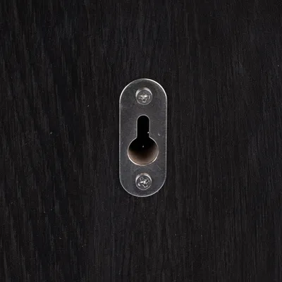 Suport de perete din metal cu două șuruburi pe suprafață de lemn neagră, potrivit pentru fixarea mobilierului sau accesoriilor.