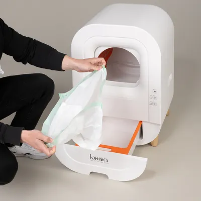 Person showing the replacement of a bin liner in a white kooa cat litter box with pull-out drawer and side controls.