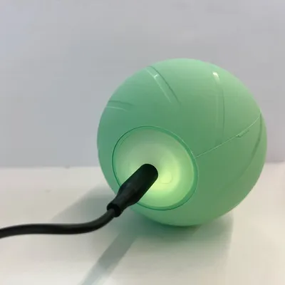 Groene bol met USB-kabelaansluiting, licht groen op. Toont laadfunctie van het product.