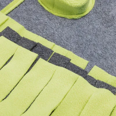 Detailaufnahme eines grauen und gelben Filzmaterials mit Fransen, möglicherweise Teil eines Tierzubehörs oder Spielzeugs.